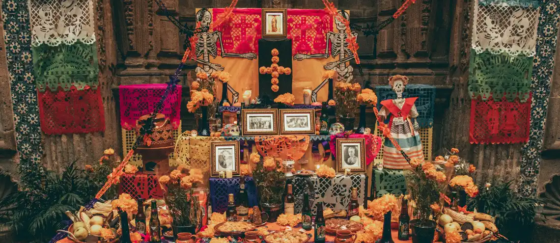 An altar elegantly decorated with skull figures, colorful clothes, and bright yellow marigolds