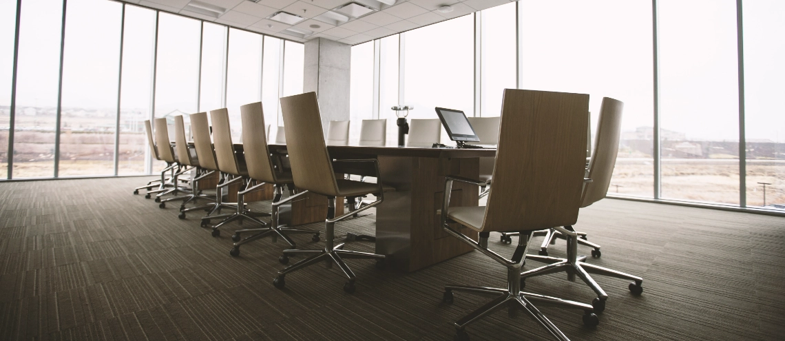 An oval brown wooden conference table and empty chairs inside a conference room